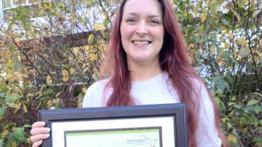 Woman standing outside holding framed award