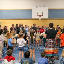 Student standing in a circle and drumming in front of other students and school community