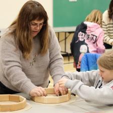 Indigenous Mentor working with student to make a drum