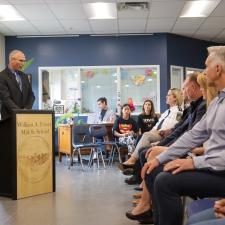 Principal Levings stands at podium in front of audience, speaking about the project